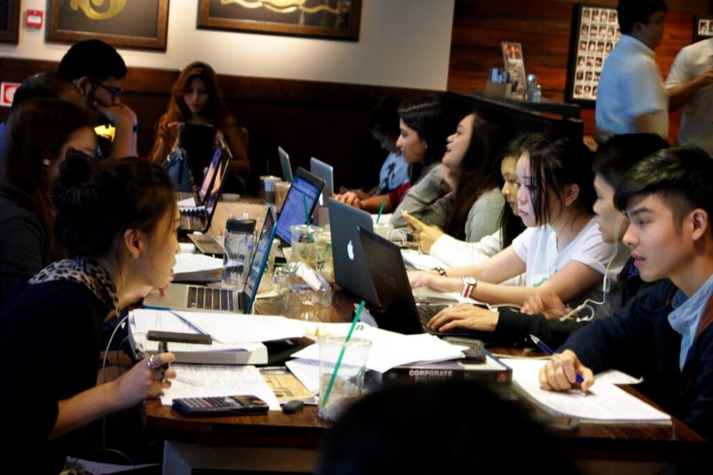 Estudantes resolvendo questões de concursos em uma mesa de estudos