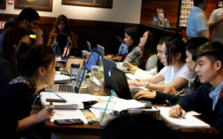 Estudantes resolvendo questões de concursos em uma mesa de estudos