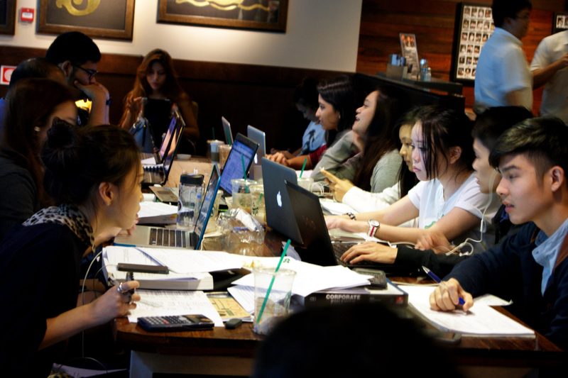 Estudantes resolvendo questões de concursos em uma mesa de estudos