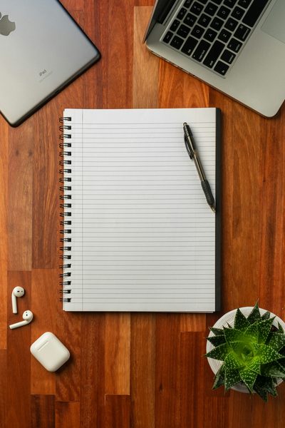 Caderno e computador usados para revisar questões de concurso