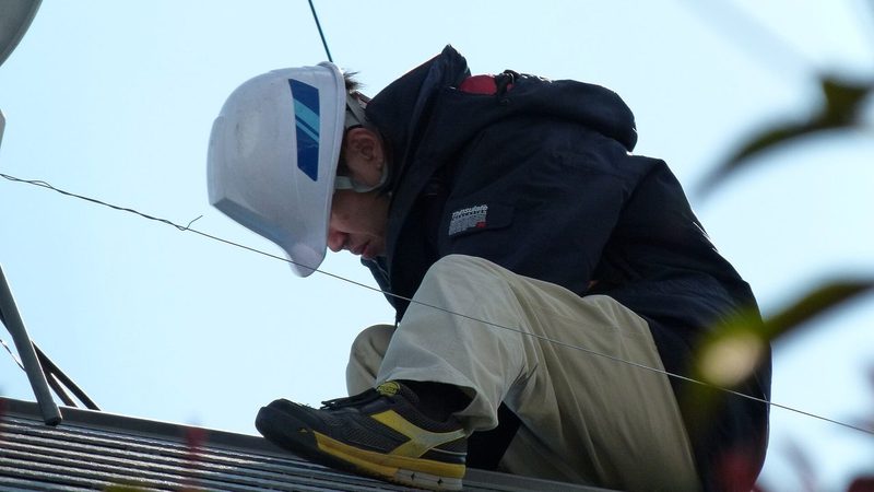 Técnico em eletrotécnica realizando instalação de painel solar em telhado