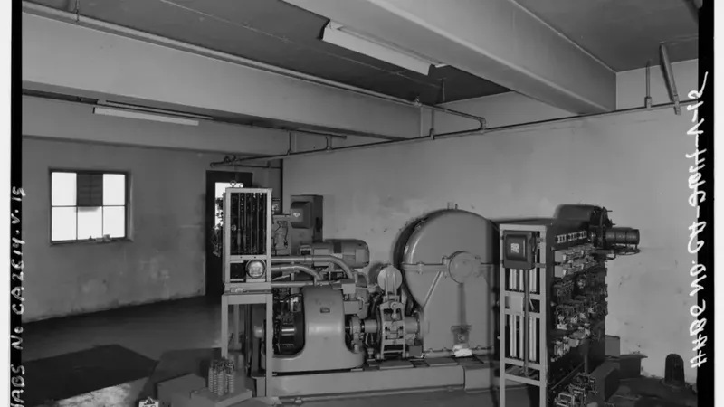 Técnico em eletromecânica diante de painéis e equipamentos de uma sala de controle