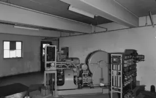 Técnico em eletromecânica diante de painéis e equipamentos de uma sala de controle