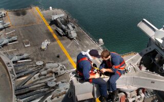 Técnicos em eletrônica fazem manutenção em equipamento de radar