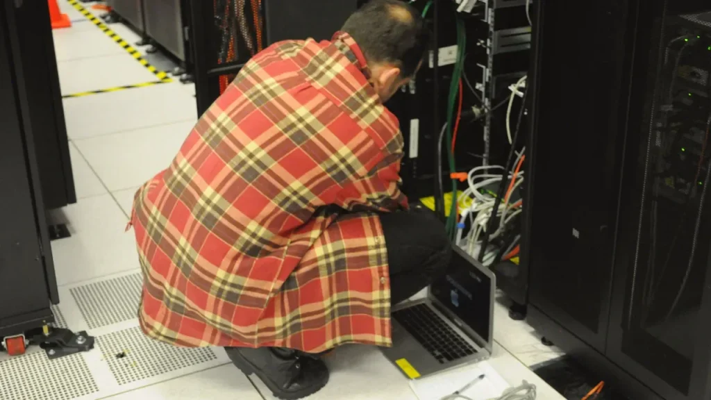 Técnico em Informática trabalhando em um rack de servidores, imagem relacionada a funções de infraestrutura e inteligência artificial