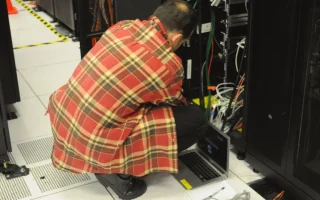 Técnico em Informática trabalhando em um rack de servidores, imagem relacionada a funções de infraestrutura e inteligência artificial