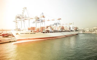 Navio porta-contêineres atracado em terminal portuário, imagem sobre técnico em Comércio Exterior e drawback