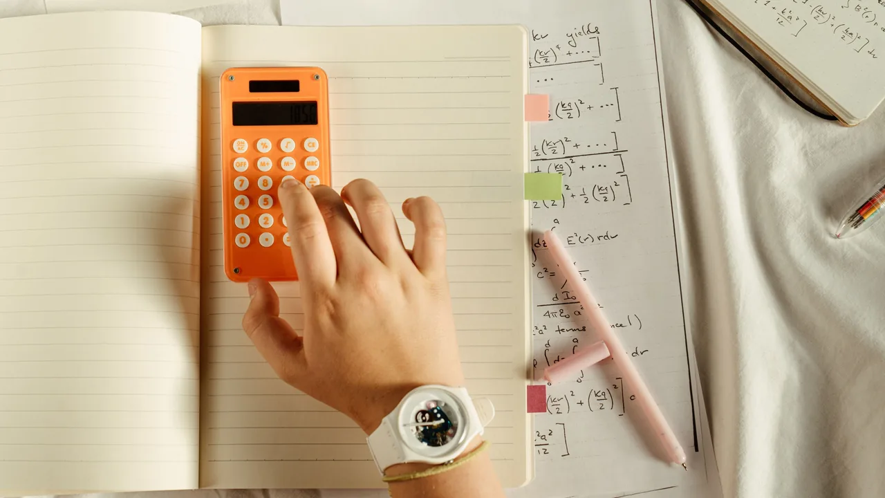 Estudante de Administração e Contabilidade usando calculadora durante os estudos