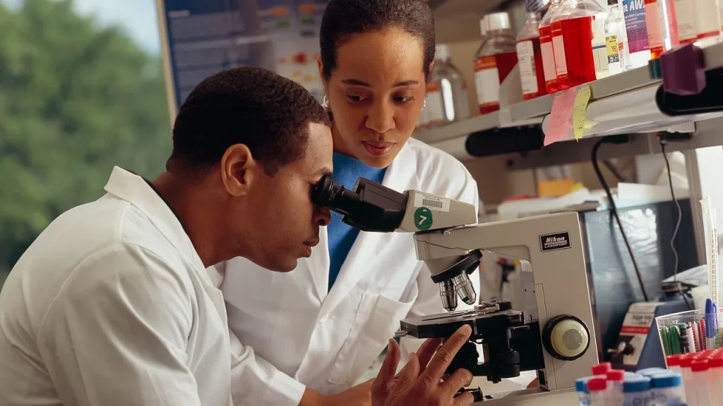Técnico em Farmácia em laboratório de análises clínicas diante de microscópio