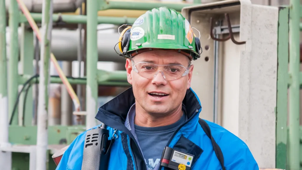 Curso técnico em Segurança do Trabalho: profissional usando capacete e óculos de proteção em ambiente industrial