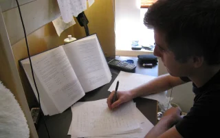 Pessoa estudando com livro, anotações e calculadora para ilustrar banco de questões para concurso