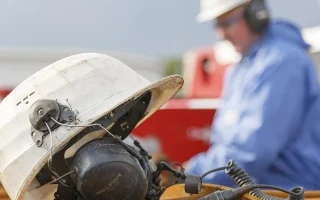 Técnico em Segurança do Trabalho em ambiente industrial com capacete e proteção auditiva