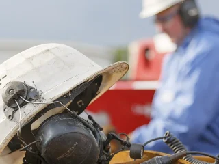 Técnico em Segurança do Trabalho em ambiente industrial com capacete e proteção auditiva
